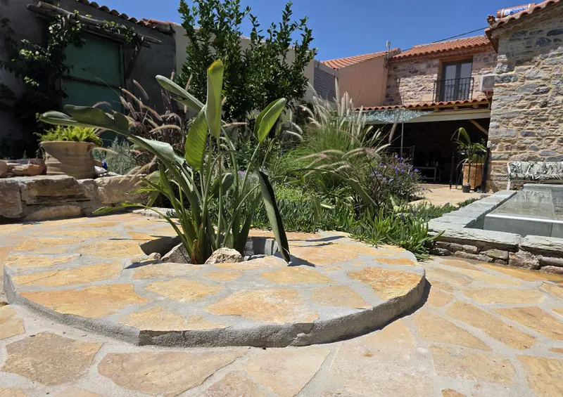 Ronde flagstone-binnenplaats met siergrassen en een strelitzia
