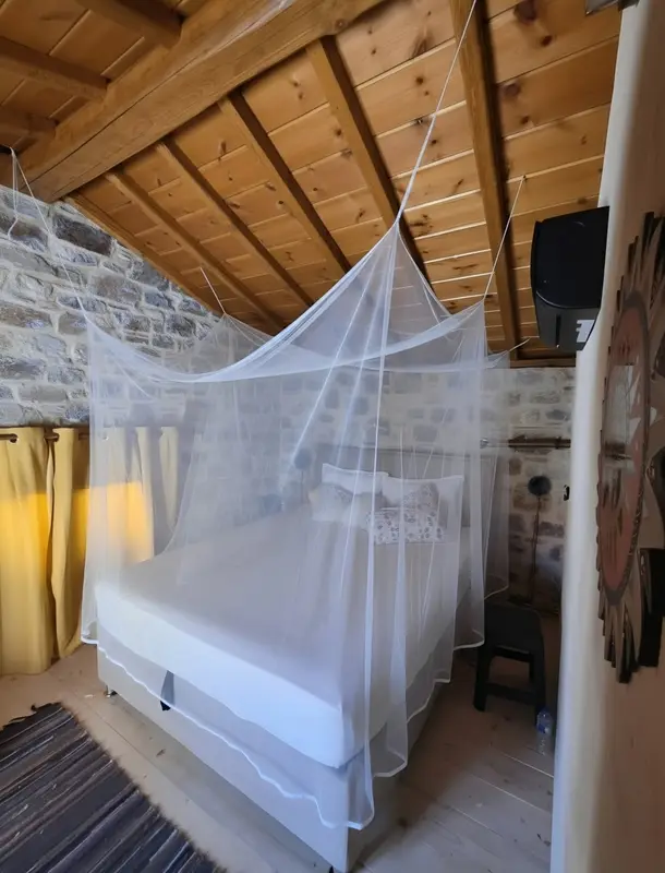 Slaapkamer met klamboe boven het bed en een houten plafond