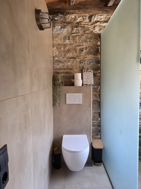 Toilet met natuurstenen wand en een balk aan het plafond