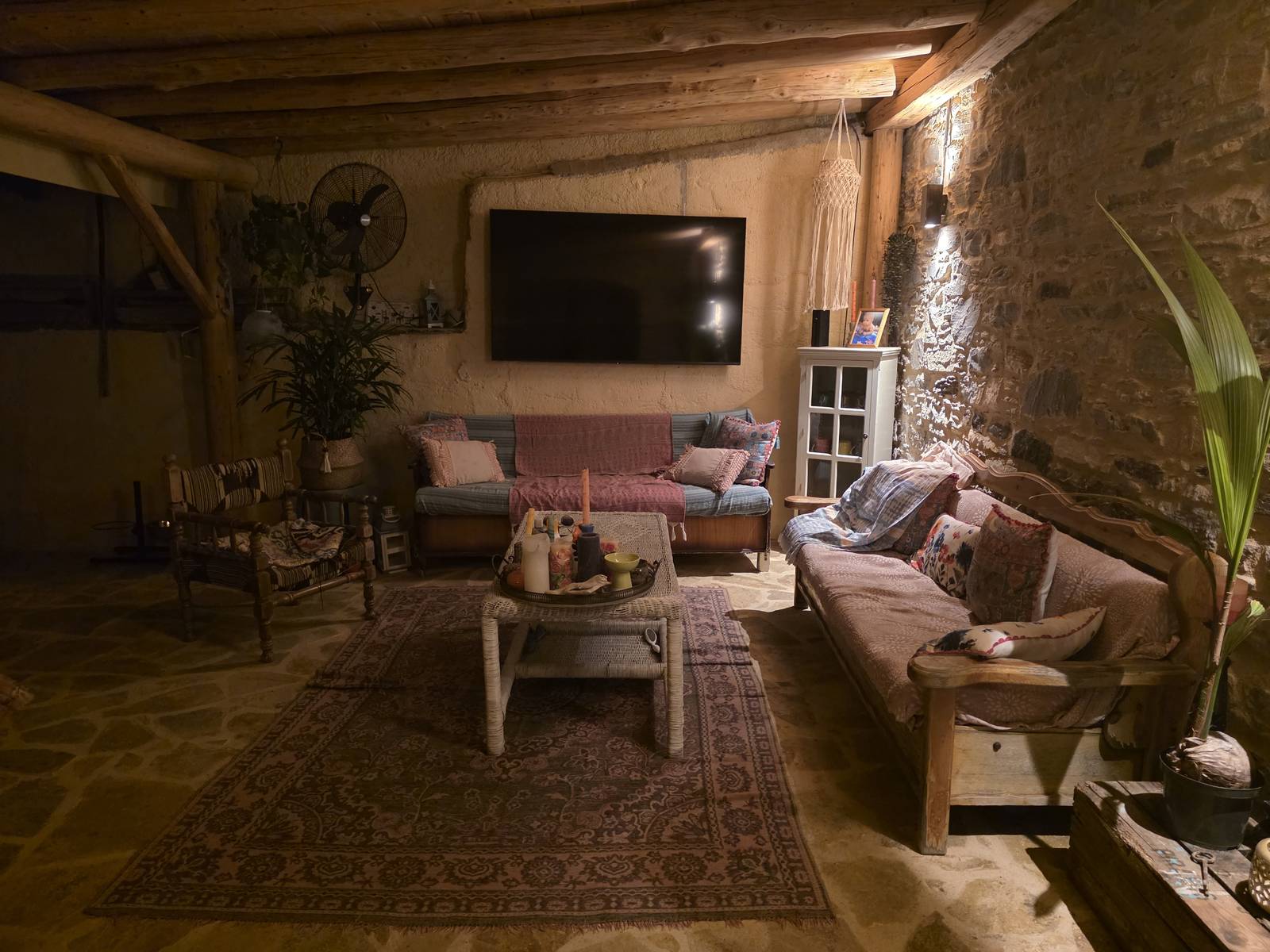 Woonkamer bij avond, warm licht onder de houten balken